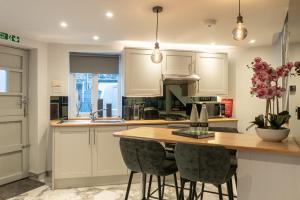 a kitchen with white cabinets and a table with chairs at The Old Coach House- luxury Harrogate Home Detached Quite Stylish whole house short walk from the Conference- town centre in Harrogate