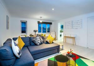 uma sala de estar com um sofá azul e almofadas amarelas em Southsea Luxury Apartment em Portsmouth