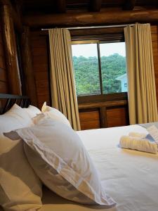 Schlafzimmer mit einem Bett und einem großen Fenster in der Unterkunft Pousada Vale Das Águias in Jaguaruna