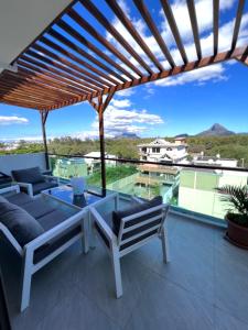 een patio met banken en een glazen tafel bij Top-Floor Modern 3BD Penthouse with Beautiful Mountain View Terrace - 5 min Walk to Beach in Flic-en-Flac