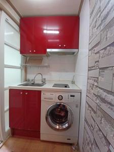 a kitchen with a washing machine and red cabinets at Dongdaemun Studio in Seoul