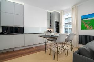 a kitchen with white cabinets and a table and chairs at GuestReady - Luxury Central London Apartment in London