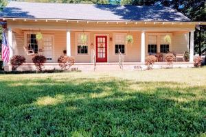une maison avec une porte rouge sur une cour dans l'établissement Historic 2-Bedroom Cloverdale Cottage, à Montgomery