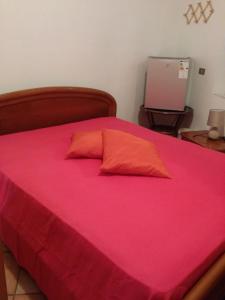 uma cama com uma colcha rosa e uma almofada vermelha em Short-lets affittacamere em Montemitro
