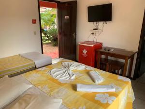 a room with two beds and a desk and a television at Hotel Praia Bonita in Capão da Canoa