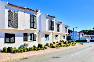 a white building with black shutters on a street at Vale do Lobo Apartment B in Vale do Lobo