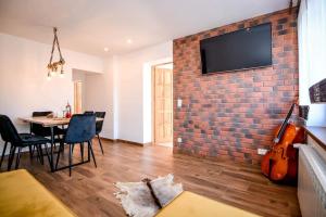 Apartamenty u Burego في بياى دوناجك: غرفة معيشة مع جدار من الطوب مع تلفزيون