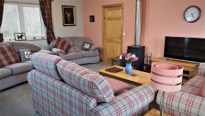a living room with two couches and a tv at Roe Deer Cottage in Beauly