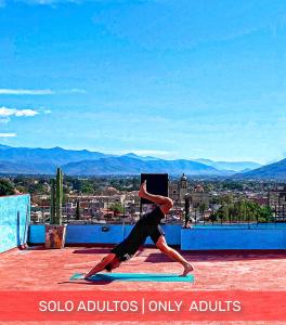a person doing a yoga pose on top of a roof at Yabanhi Hostel in Oaxaca City