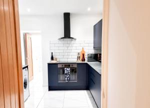 a kitchen with blue cabinets and a stove at Spacious 3-bed near the city centre in Swansea