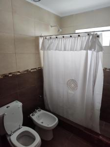 Un baño con inodoro y cortina de ducha en Los departamentos de Eva, en San Antonio Oeste