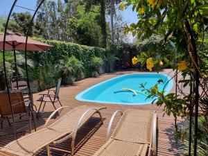 a swimming pool with chairs and an umbrella at Casa do Mato ! Lugar de descanso e Paz !-Next Iguassu Falls in Foz do Iguaçu