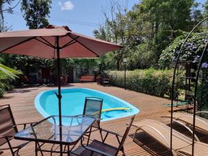 una mesa con sillas y una sombrilla junto a la piscina en Casa do Mato ! Lugar de descanso e Paz !-Next Iguassu Falls en Foz de Iguazú
