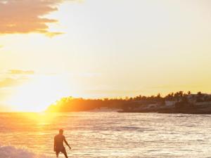 a man walking in the water on a beach at OceanBlue Resort in Christ Church