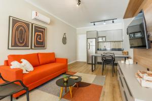 sala de estar con sofá naranja y cocina en Estudio pratico no Centro de Floripa, 900 metros do CentroSul P1617, en Florianópolis