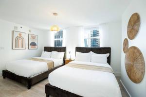 deux lits dans une chambre avec des murs et des fenêtres blancs dans l'établissement City views at brickell miami, à Miami 25 autres photos