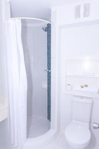 a white bathroom with a shower and a toilet at OceanBlue Resort in Christ Church