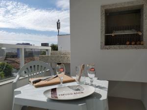 een witte tafel met twee wijnglazen op een balkon bij 2 quadras da Praia em Canasvieiras, Piscina e Churrasqueira P1595 in Florianópolis
