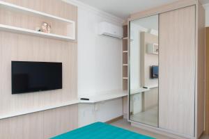 een woonkamer met een tv en een spiegel bij 2 quadras da Praia em Canasvieiras, Piscina e Churrasqueira P1595 in Florianópolis