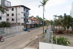 een lege straat met een hek en palmbomen bij 2 quadras da Praia em Canasvieiras, Piscina e Churrasqueira P1595 in Florianópolis