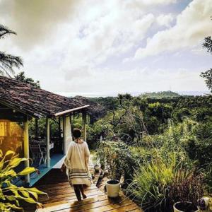 uma mulher a andar num deque de madeira em Eco-Pousada Casa Bobô na Ilha de Boipeba