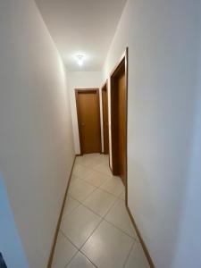 pasillo con 2 puertas y suelo de baldosa en Apartamento Aconchegante, en Bombinhas