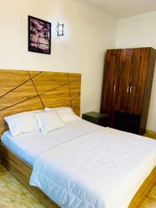a bedroom with a large bed with a wooden headboard at Lovely Studio apartment at Ajah - Maria in Iranla
