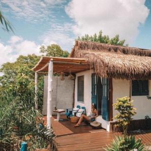uma mulher sentada no alpendre de uma casa em Eco-Pousada Casa Bobô na Ilha de Boipeba