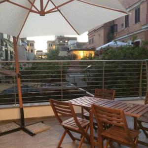 een tafel en stoelen met een parasol op een balkon bij Centro storico, nuovo con terrazzo in Lido di Ostia