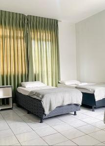 two beds sitting in a room with curtains at Hotel Central de Anápolis in Anápolis