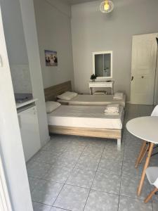 Cette petite chambre comprend deux lits et une table. dans l'établissement BYZANTIUM APARTMENTS, à Ermoúpoli