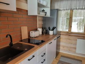 a kitchen with white cabinets and a sink and a brick wall at Suurepera puhkekeskuse saunamaja 