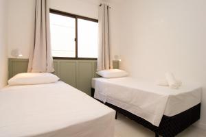 Duas camas num quarto com uma janela em Apto aconchegante a 400 metros da Praia nos Ingleses Norte P1562 em Florianópolis