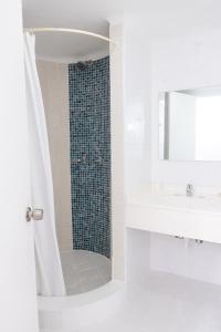 a white bathroom with a shower and a sink at OceanBlue Resort in Christ Church