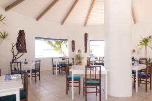 a dining room with white tables and chairs at OceanBlue Resort in Christ Church