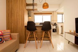 sala de estar con 2 sillas negras y cocina en Apto aconchegante a 400 metros da Praia nos Ingleses Norte P1562, en Florianópolis