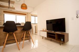 2 sillas negras en la sala de estar con TV de pantalla plana en Apto aconchegante a 400 metros da Praia nos Ingleses Norte P1562, en Florianópolis