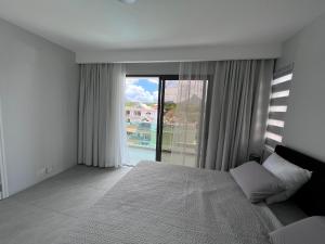 a bedroom with a bed and a large window at Top-Floor Modern 3BD Penthouse with Beautiful Mountain View Terrace - 5 min Walk to Beach in Flic-en-Flac +33 photos