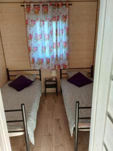 dwa łóżka w pokoju z oknem w obiekcie Domki Brzózki Kosewo w mieście Kosewo