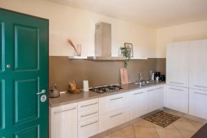 una cocina con armarios blancos y una puerta verde en Lago di Garda a 300m House in Manerba, en Manerba del Garda