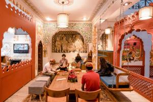 un grupo de personas sentadas alrededor de una mesa en una habitación en Madpackers Pushkar en Pushkar