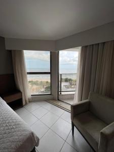 1 dormitorio con cama, silla y ventana grande en FLAT BEACH CLASS INTERNATIONAL APTo 808, en Recife