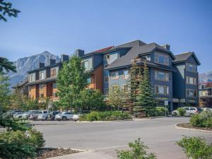 un gran edificio con coches estacionados en un estacionamiento en NEW! UPDATED Attractive Downtown Condo! Sleeps 10, Hot Tub, Mountain View, en Canmore