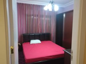 a bedroom with a pink bed with a black headboard at Dream Home in Amman