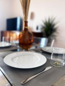 einen Tisch mit einer weißen Platte und einem Glas in der Unterkunft Le Sorbier, Style Appart'Hôtel, vers la gare, by PRIMO C0NCIERGERIE in Nevers