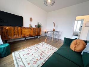 ein Wohnzimmer mit einem Sofa und einem Flachbild-TV in der Unterkunft Le Sorbier, Style Appart'Hôtel, vers la gare, by PRIMO C0NCIERGERIE in Nevers