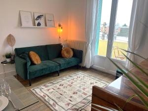 a living room with a green couch and a window at Le Sorbier, Style Appart'Hôtel, vers la gare, by PRIMO C0NCIERGERIE in Nevers