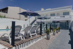 a row of chairs and an umbrella next to a pool at Saint Uriel in Puerto Madryn
