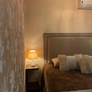 1 dormitorio con 1 cama y 1 lámpara en una mesa en Apto Luxo Centro Gramado en Gramado