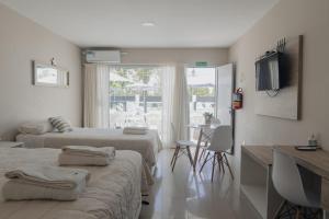 um quarto com duas camas e uma mesa e uma televisão em Saint Uriel em Puerto Madryn
